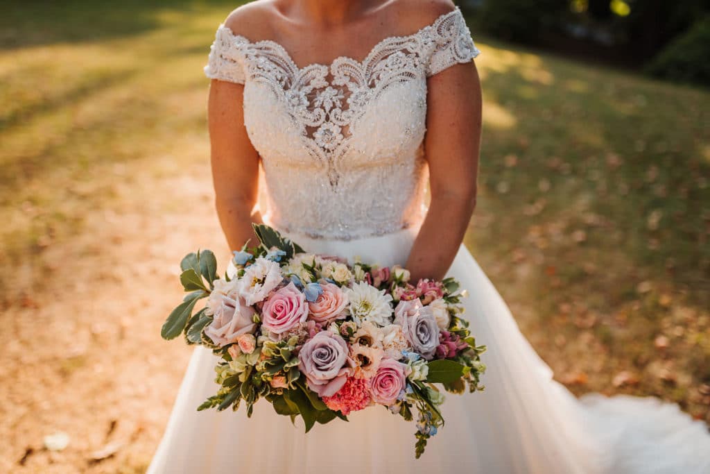 Nevesta drži v roki poročni šopek pastelnih barv