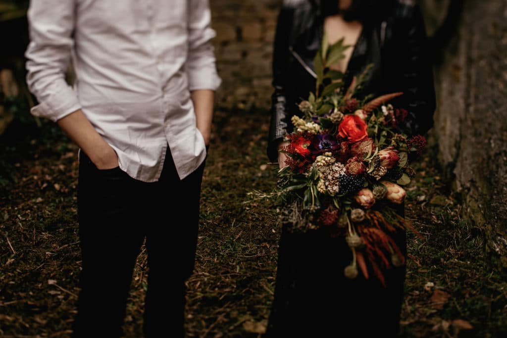 Nevesta in ženin v dark stilu s poročnim šopkom iz ranuncul