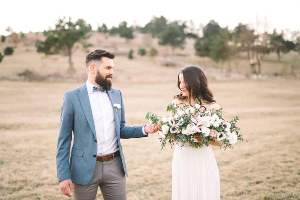 Ženin in nevesta s pomladnim šopkom se držita za roko