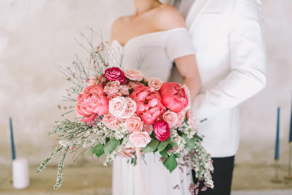 ženin objema nevesto s poročnim šopkom iz koralnih potonik