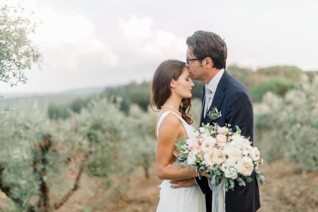 Nevesta in ženin v objemu z modernim poročnim šopkom na posestvu Toskanske domačije