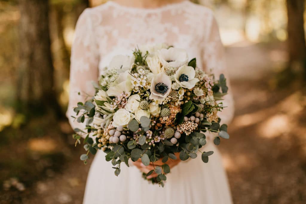 Nevesta stoji v gozdu in drži vintage poročni šopek